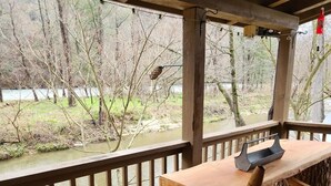 A wooden deck with a table and chairs overlooking a river.
