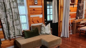 A cozy cabin interior with a wooden interior, a sofa set, and a dining area.