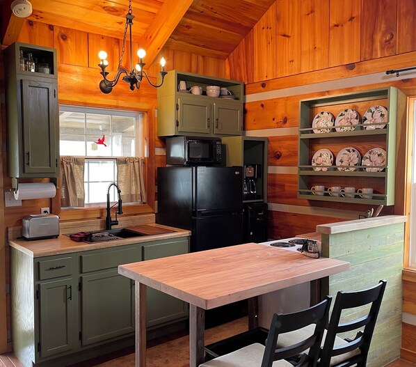 A cozy cabin-style kitchen with wooden walls, a central island, and a dining area.
