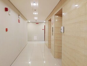 Un corridoio pulito e ben illuminato, con pavimento piastrellato, attrezzature di emergenza e una porta con il numero 512.