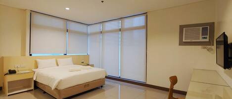A hotel room with a bed, bedside tables, a desk, and a chair.