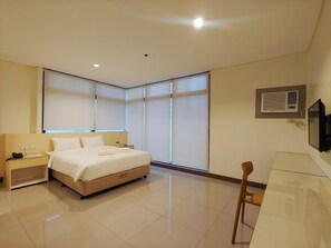 Une chambre d’hôtel avec un lit, des tables de chevet, un bureau et une chaise.