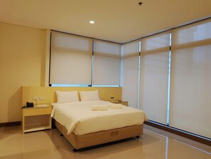 Ein modernes Schlafzimmer mit einem großen Bett, Nachttischen und einem Fenster mit Jalousien.