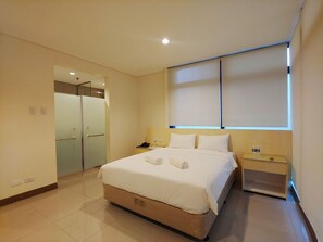 A hotel room with a bed, bedside table, and a window with blinds. - Reddoorz Plus @ Kaizen Suites Taft Avenue (Manila)