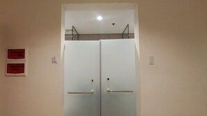 A double door with a metal handle, a light switch, and a ceiling light fixture. - Reddoorz Plus @ Kaizen Suites Taft Avenue (Manila)