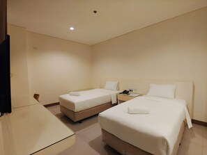 Ein Hotelzimmer mit zwei Betten, einem Schreibtisch und einem Fernseher.