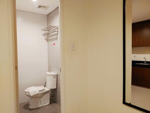A compact bathroom with a toilet, a wall-mounted towel rack, and a visible electrical outlet. - Reddoorz Plus @ Kaizen Suites Taft Avenue (Manila)