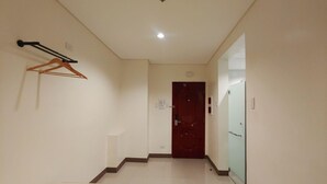 A hallway with a wooden hanger, a door, and a white wall. - Reddoorz Plus @ Kaizen Suites Taft Avenue (Manila)
