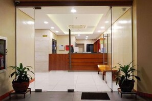 Una zona d'entrada amb taulell de recepció, una sala d'espera amb seients i plantes en testos.