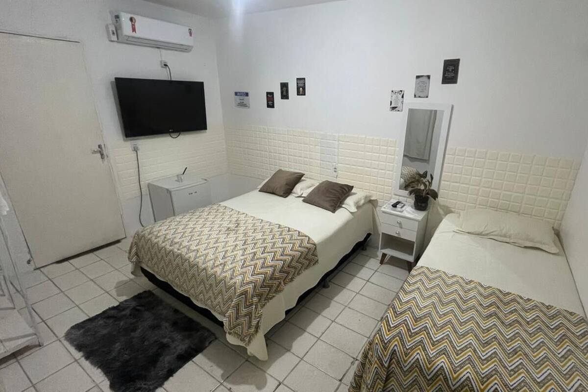 A hotel room with a bed, bedside table, TV, and a mirror.