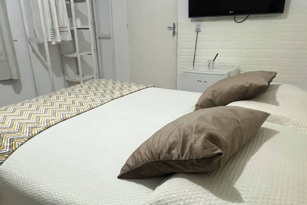 A bedroom with a bed, pillows, a TV, and a wardrobe.