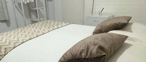 A bedroom with a bed, pillows, a TV, and a wardrobe.