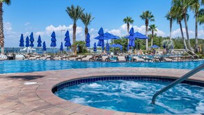 A pool area with lounge chairs and umbrellas, surrounded by palm trees.