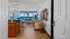 A spacious living area with a kitchen, a dining area, and a view of the ocean.