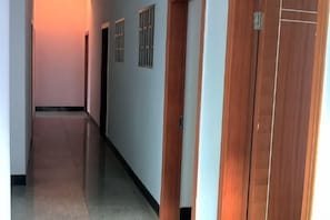A hallway with wooden doors, a tiled floor, and a plain wall. - Jiangling Guesthouse (Wuyuan)