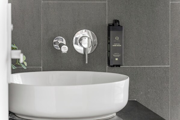 A modern bathroom with a large white sink, a chrome faucet, and a hand wash station labeled "Oxygen Collection Purifying Hand Wash White Lily". - King Street Apartments by Urban Rest (Newtown)