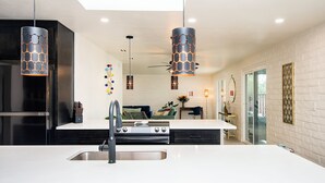 Una cocina moderna con una isla central, electrodomésticos de acero inoxidable e iluminación colgante.