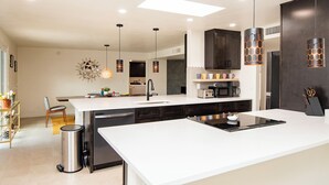 Una cocina moderna con una isla central, armarios oscuros e iluminación colgante.