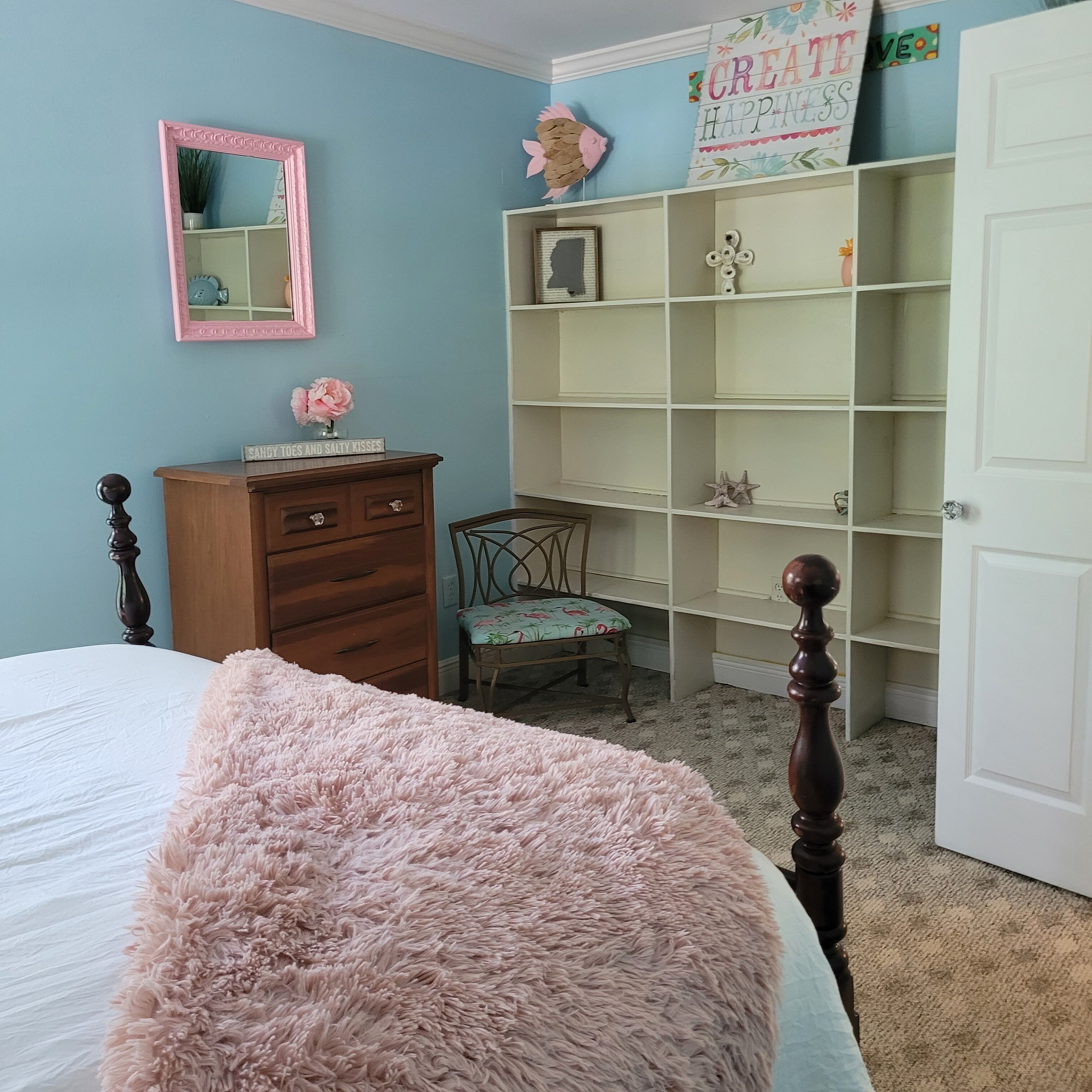 Une chambre à coucher avec un lit, une commode, une chaise et une bibliothèque.