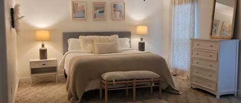 Un dormitorio con cama, lámparas de noche, ventilador de techo, cómoda y espejo.