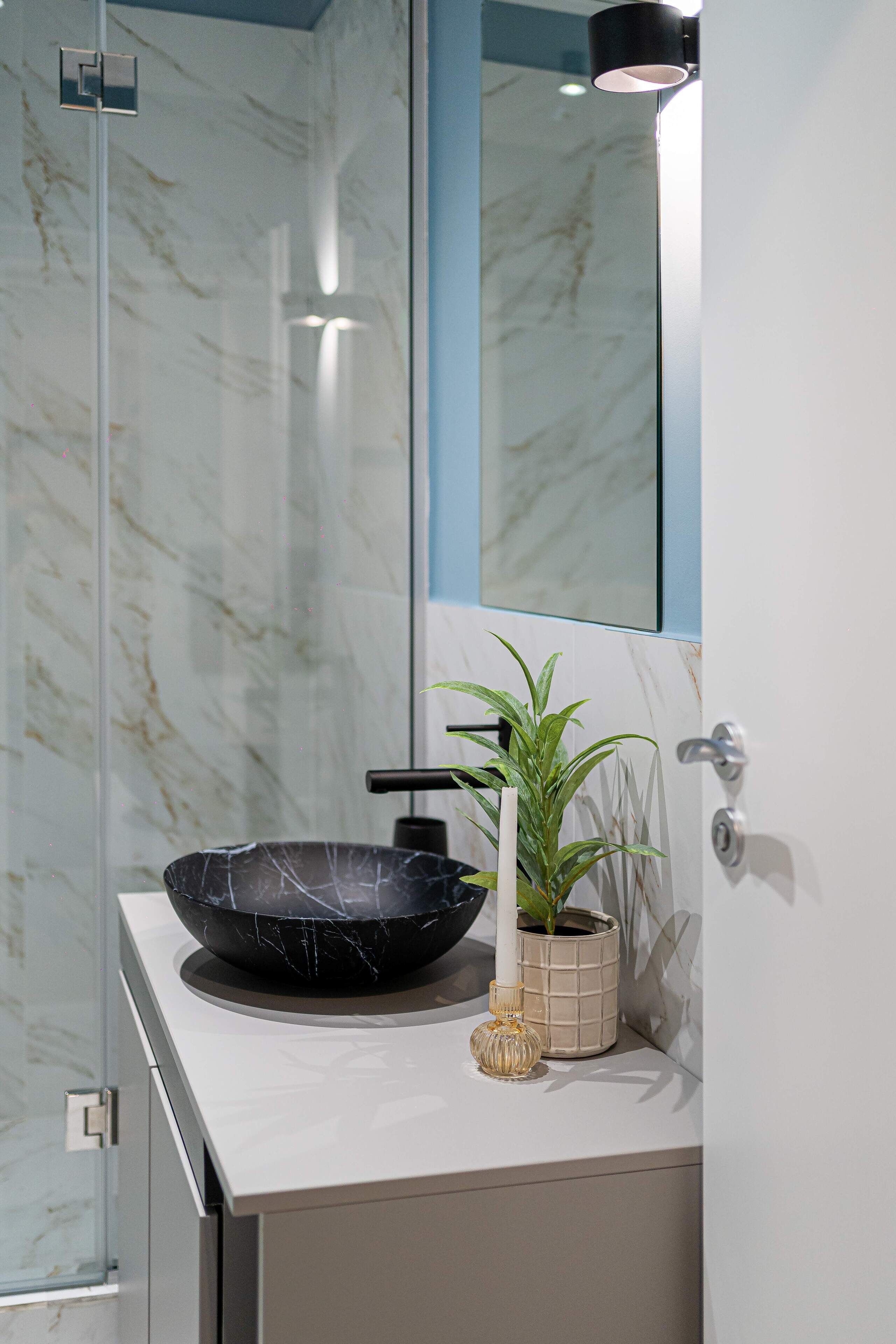 Une salle de bain avec un lavabo en marbre, une plante en pot et un miroir.