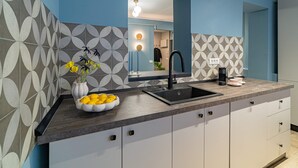 A modern kitchen with a dark countertop, white cabinets, and a black sink. - Lively Colors & Serene Comfort - Renovated 1BR by Piata Universitatii (Bucharest)