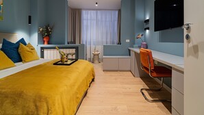A hotel room with a bed, a desk, a chair, a TV, and a window with curtains. - Lively Colors & Serene Comfort - Renovated 1BR by Piata Universitatii (Bucharest)