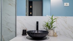 A modern bathroom with a black vessel sink, a marble backsplash, a potted plant, and a mirror above the sink. - Lively Colors & Serene Comfort - Renovated 1BR by Piata Universitatii (Bucharest)