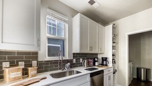 A modern kitchen with white cabinets, a stainless steel sink, and a coffee station. - 2xKing-Beds, Birkdale-Plaza-Vista, Shop-Eat-Play (Huntersville)