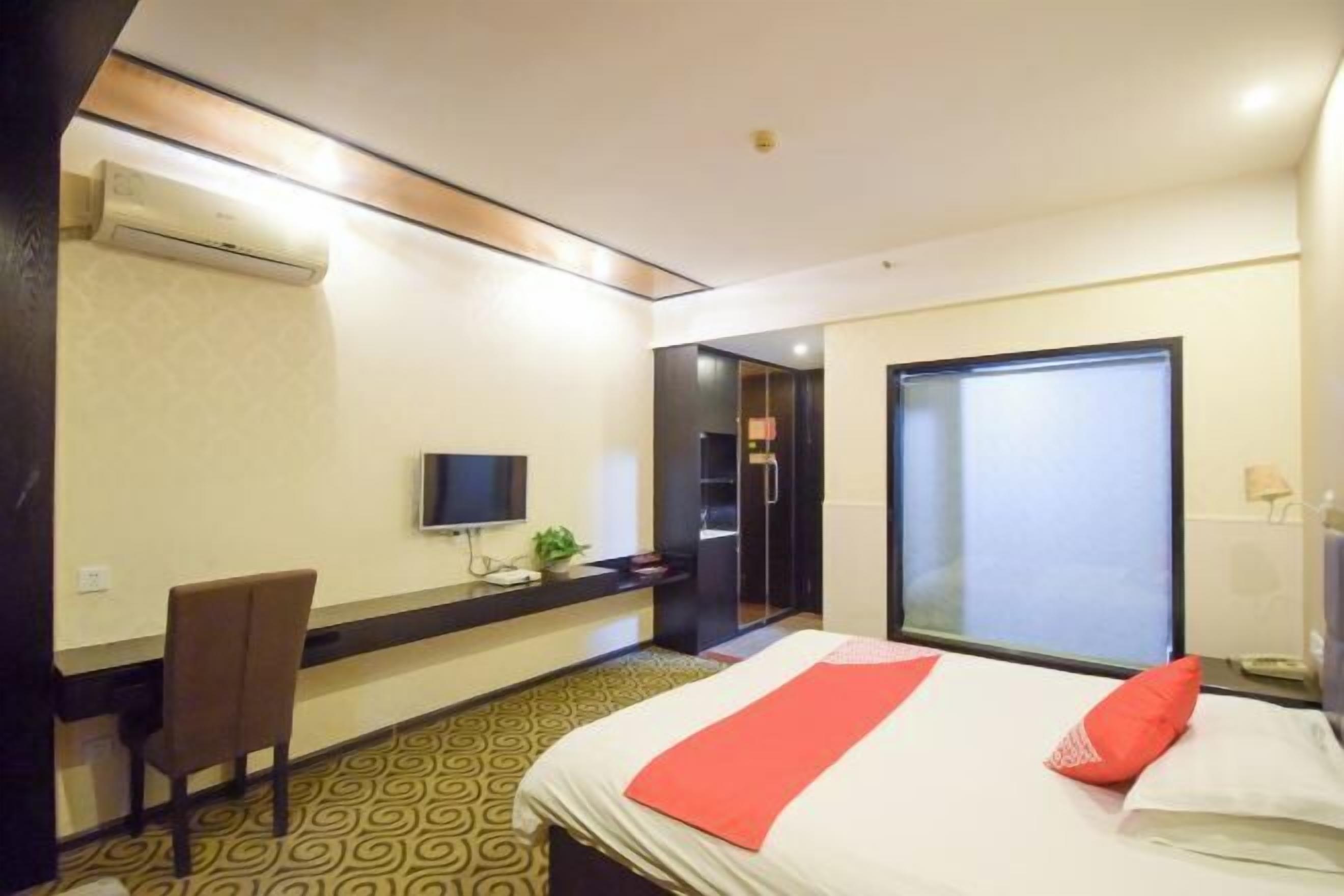 Une chambre d’hôtel équipée d’un lit, d’un bureau, d’une chaise, d’une télévision et d’un espace douche.