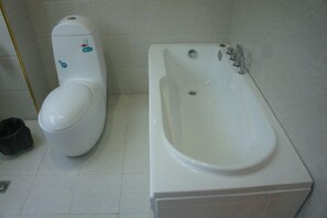 A bathroom with a toilet and a bathtub. - Lido Hotel (Linshui)