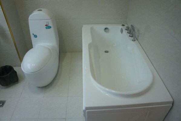 A bathroom with a toilet and a bathtub. - Lido Hotel (Linshui)