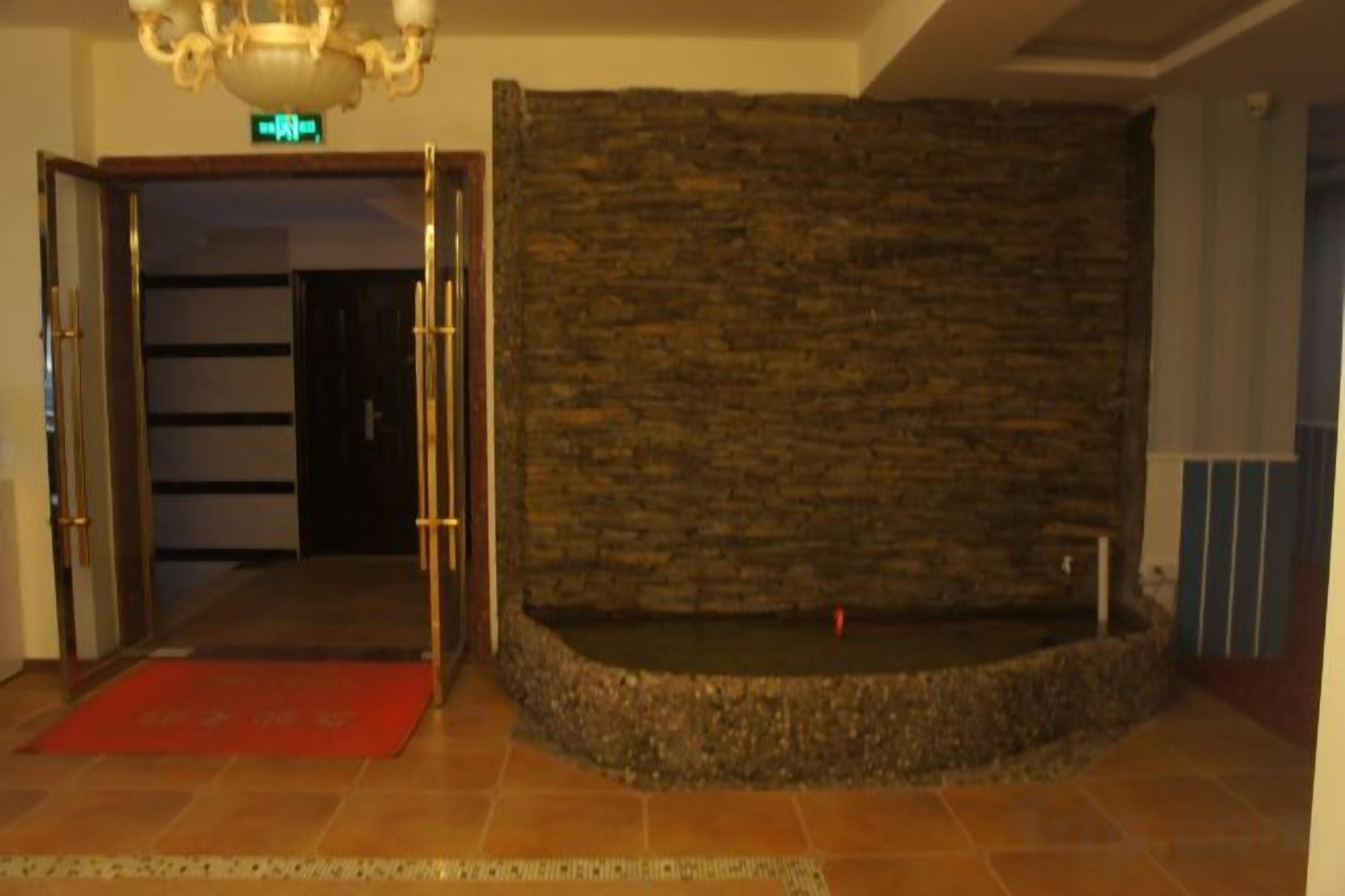 A lobby with a stone wall, a red carpet, and a door leading to another room.