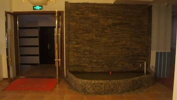 A lobby with a stone wall, a red carpet, and a door leading to another room.