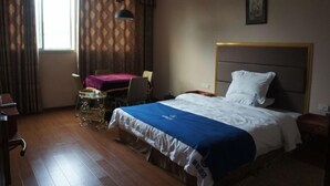 A hotel room with a bed, a desk, a chair, and a window with curtains. - Lido Hotel (Linshui)