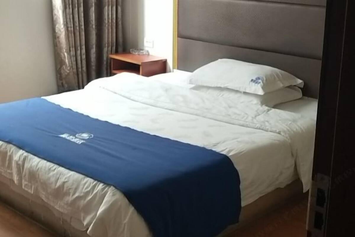 Ein Hotelzimmer mit Bett, Nachttisch und einem Fenster mit Vorhängen.
