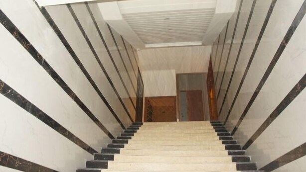 A marble staircase with black accents leading to a wooden door. - Lido Hotel (Linshui)
