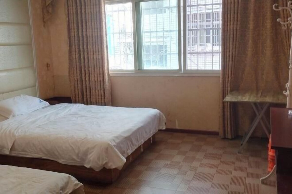 A bedroom with a single bed, a chair, and a window with curtains.