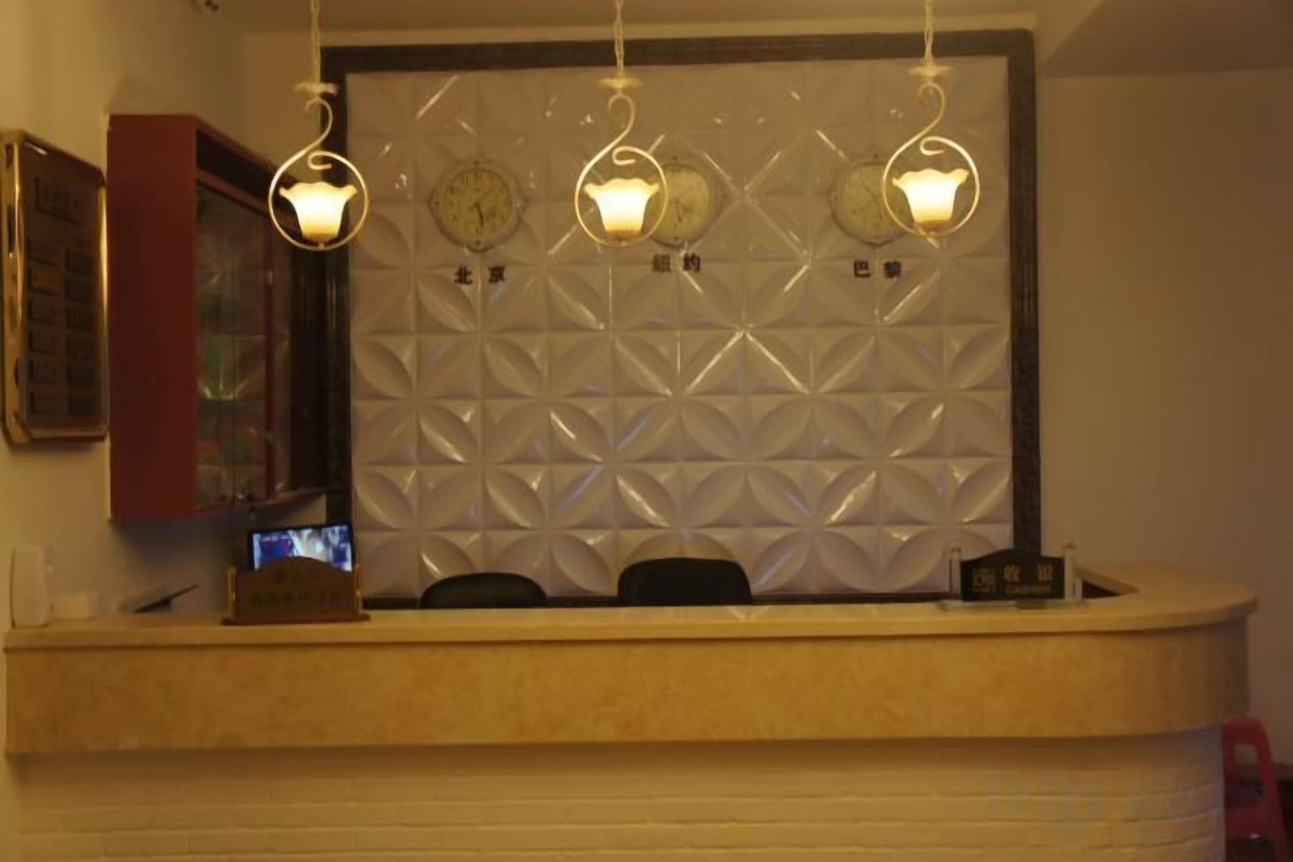 A reception area with a counter, three wall clocks, and hanging pendant lights.