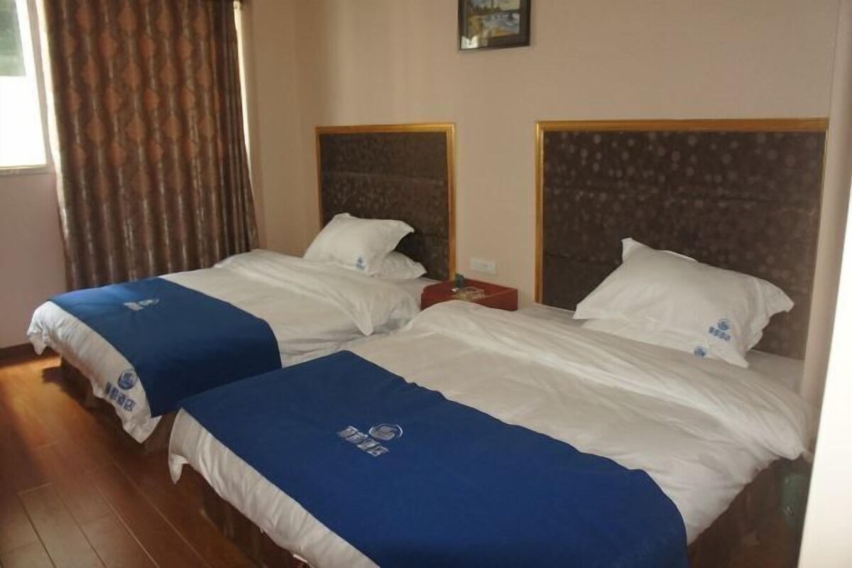 Two beds with headboards, a window with curtains, and a small red table.