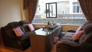 A living room with two brown sofas, a glass coffee table, and a pink mug. - Lido Hotel (Linshui)