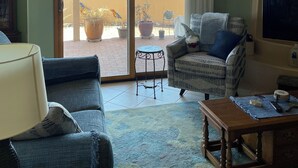 A living room with a sofa, armchair, and coffee table, a television, and a ceiling fan.