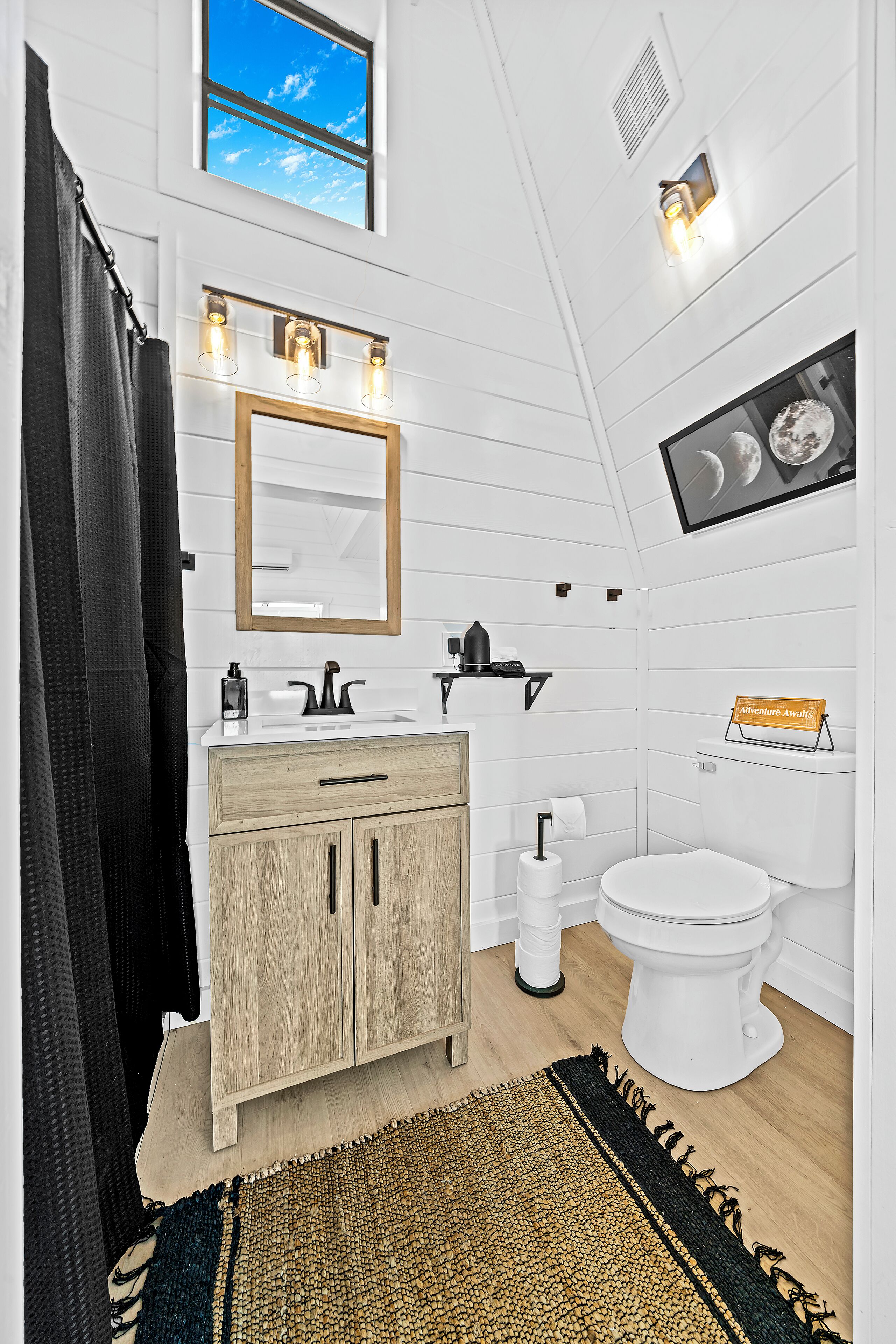 Un baño moderno con tocador de madera, un espejo grande y un inodoro.