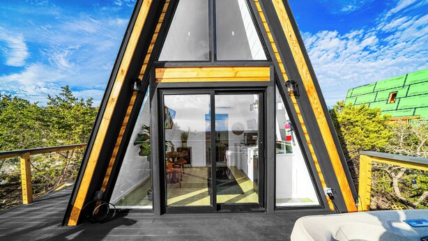 Ett modernt hus med en stor glasdörr som leder in till ett kök och en matplats.
