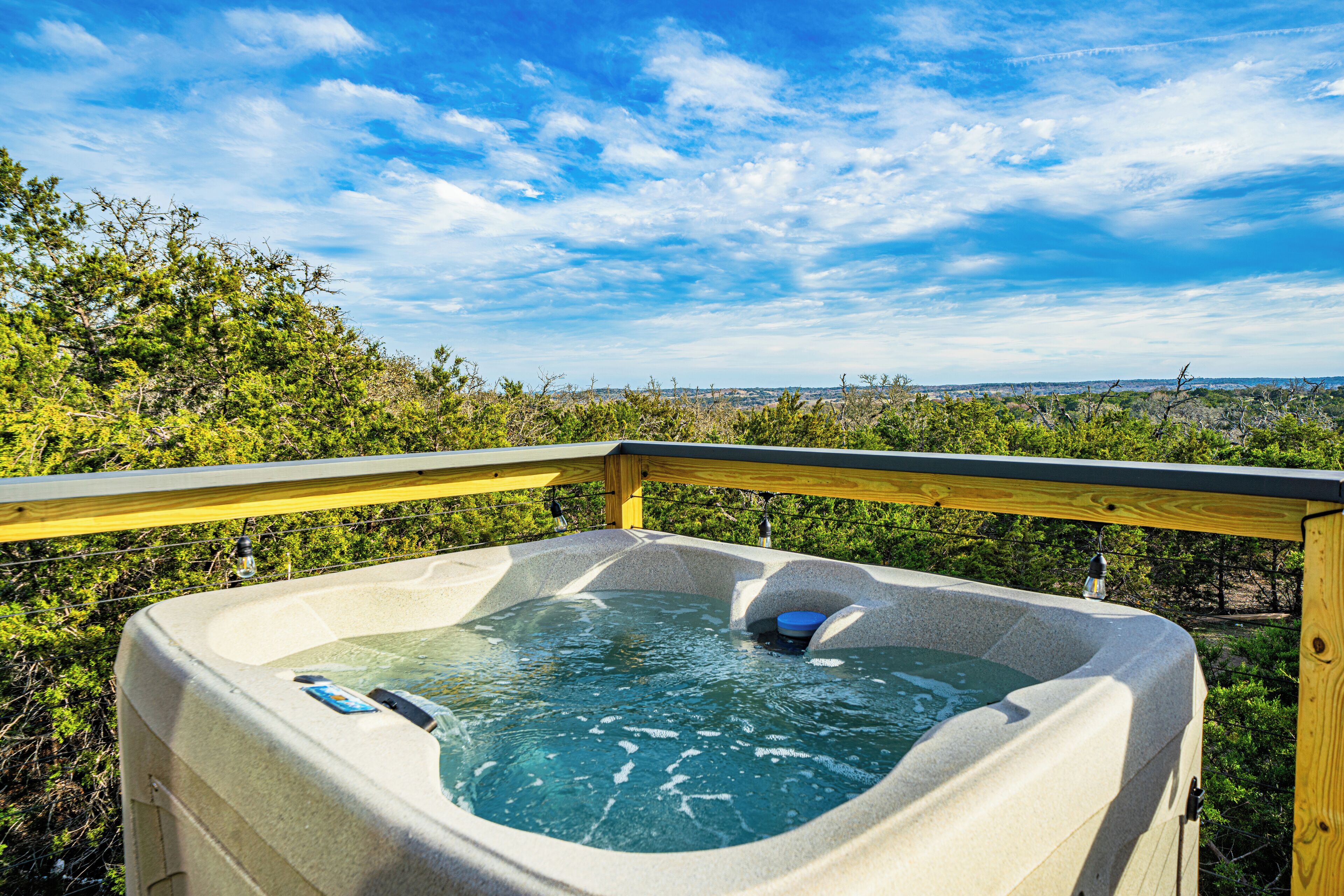Een hottub met een houten terras en een prachtig uitzicht op het landschap.