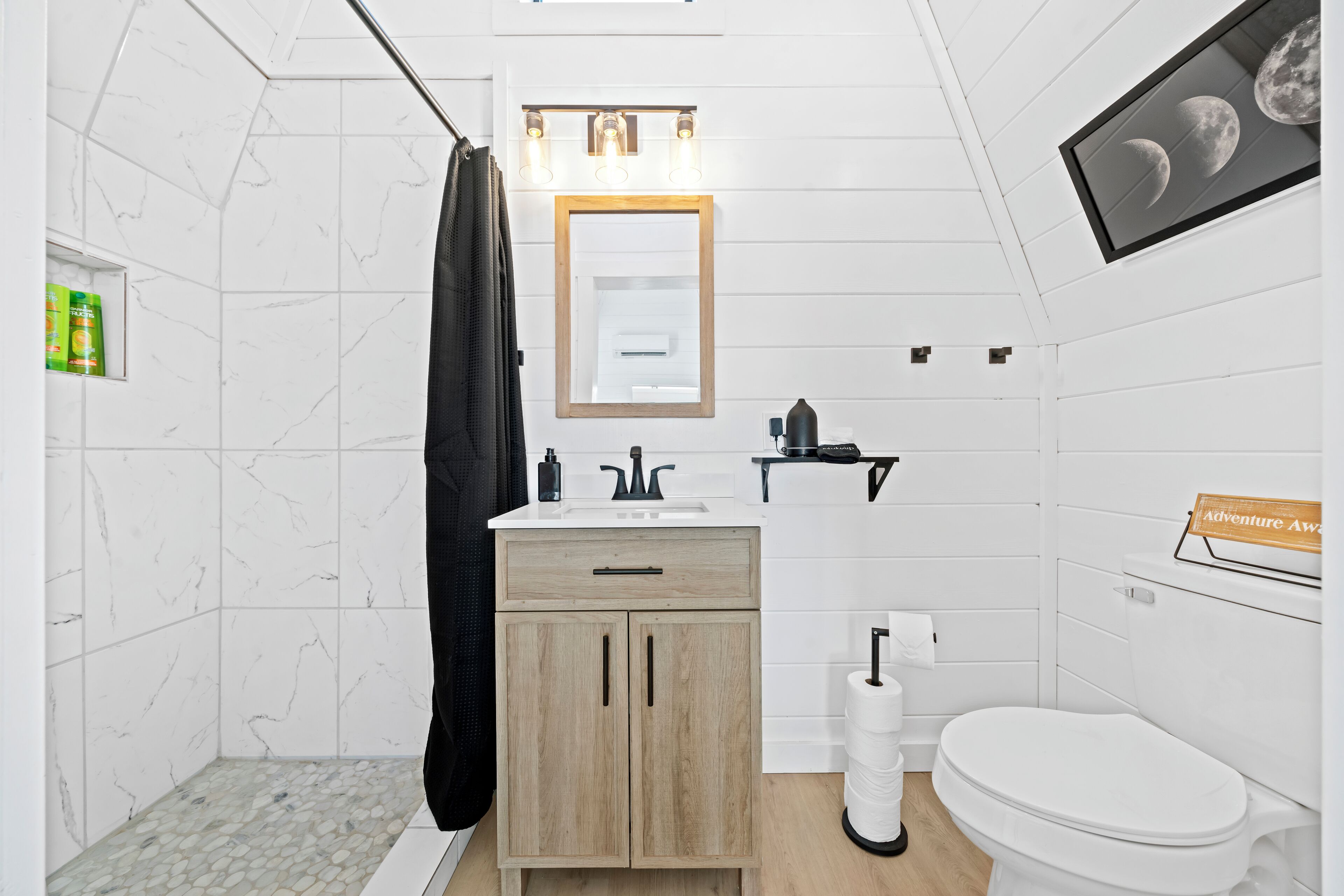 Een moderne badkamer met douche, toilet, wastafel en kast.