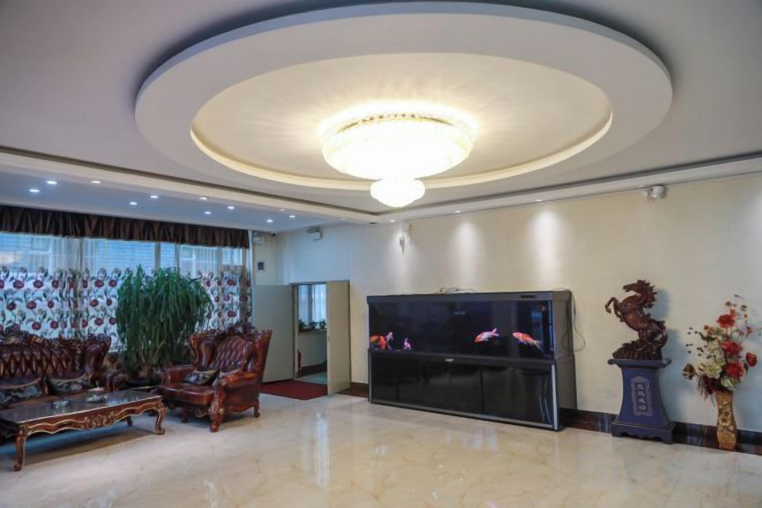 Un amplio vestíbulo con una gran televisión de pantalla plana, una araña de cristal y una zona de estar con sofá y sillones.
