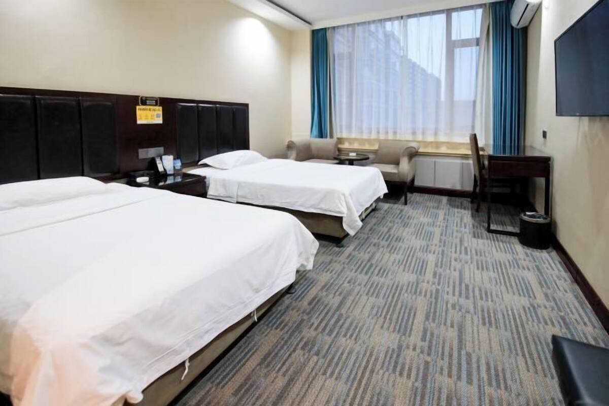 Une chambre d’hôtel avec deux lits, un canapé, une petite table et un téléviseur.