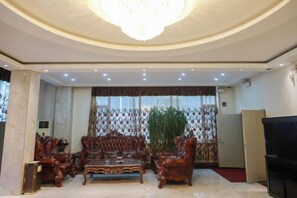 A spacious living room with a large chandelier, a sofa set, and a television.