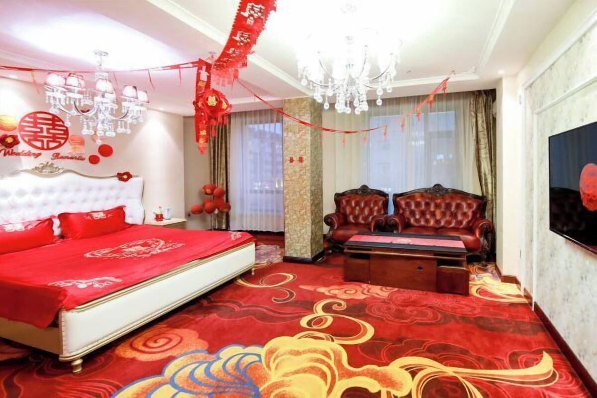 Une chambre d’hôtel avec un lit, un canapé, une télévision et un lustre.